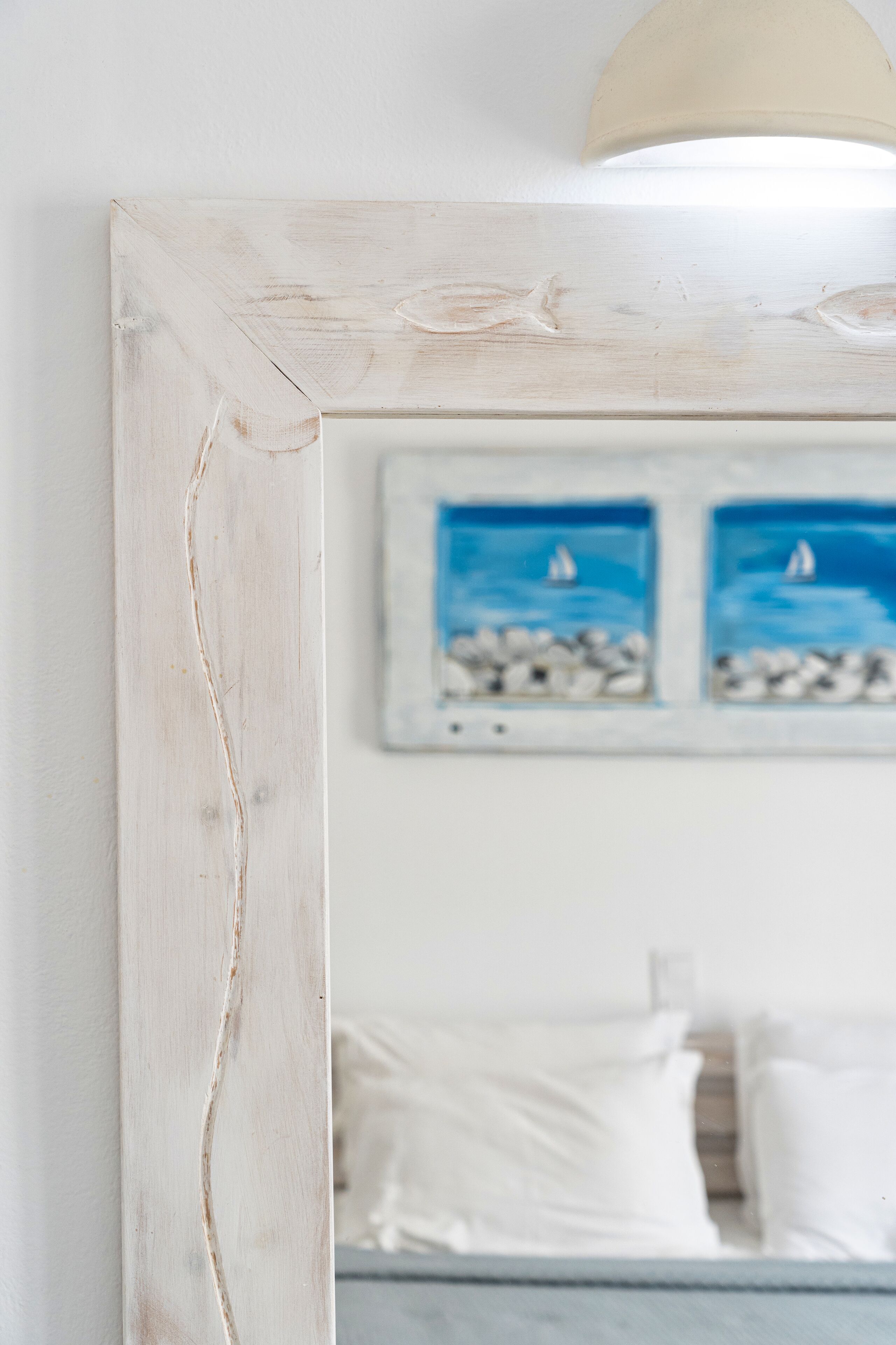 A bedroom with a bed, white pillows, and a framed picture of a beach scene.