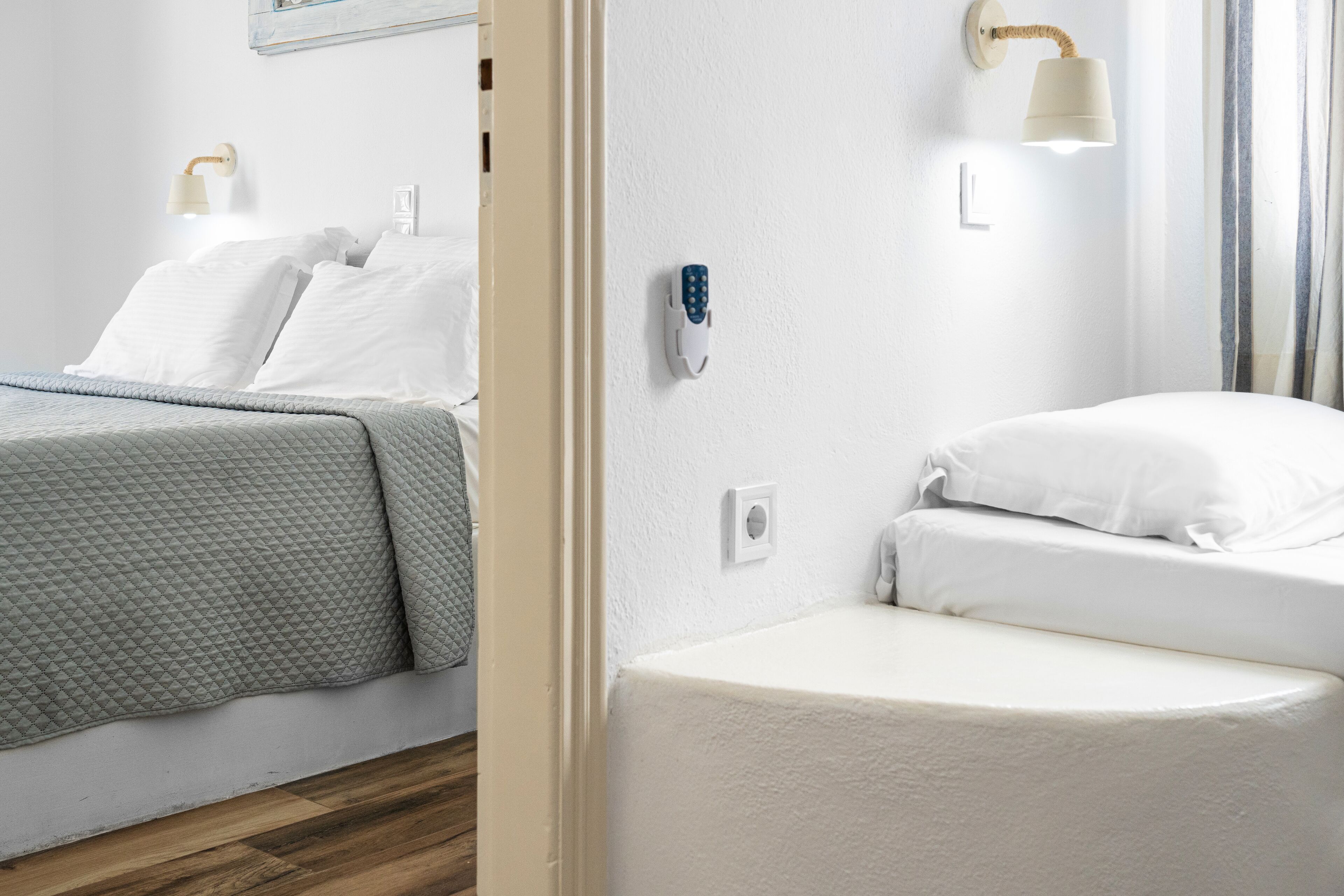 Une chambre d’hôtel avec un lit, une table de chevet, une lampe fixée au mur et une porte.