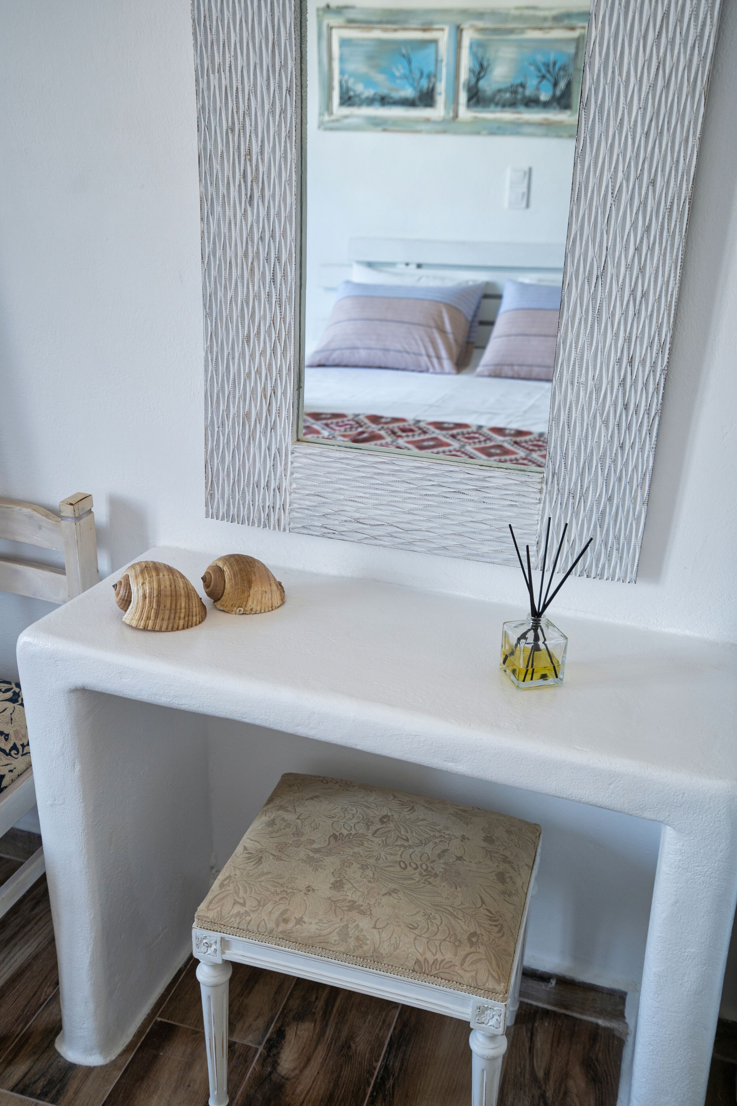 A white vanity with two seashells and a glass container with reed sticks.