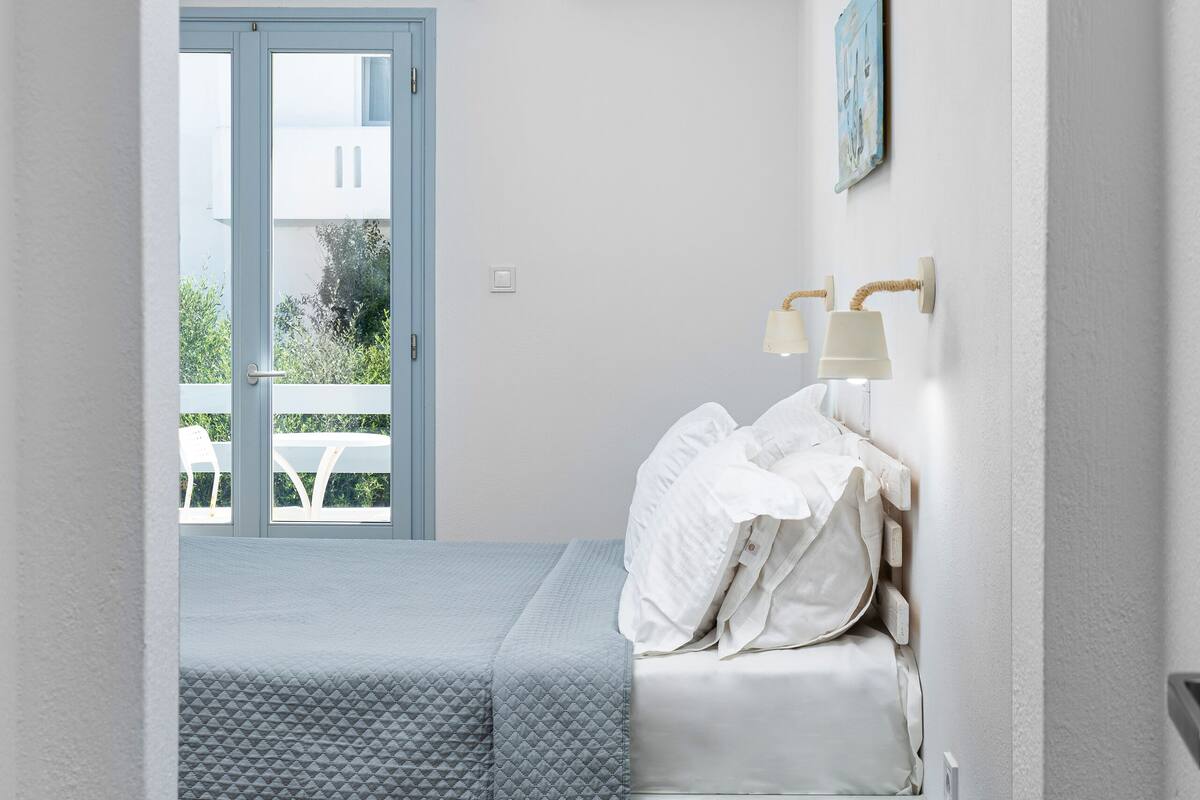 A bedroom with a bed, bedside table, and a window.