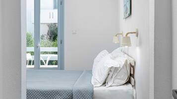 Un dormitorio con cama, mesita de noche y ventana.