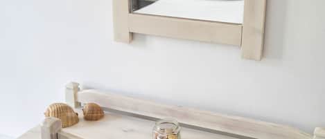 Een houten bureau met een gevlochten mand, een glazen pot en twee schelpen.