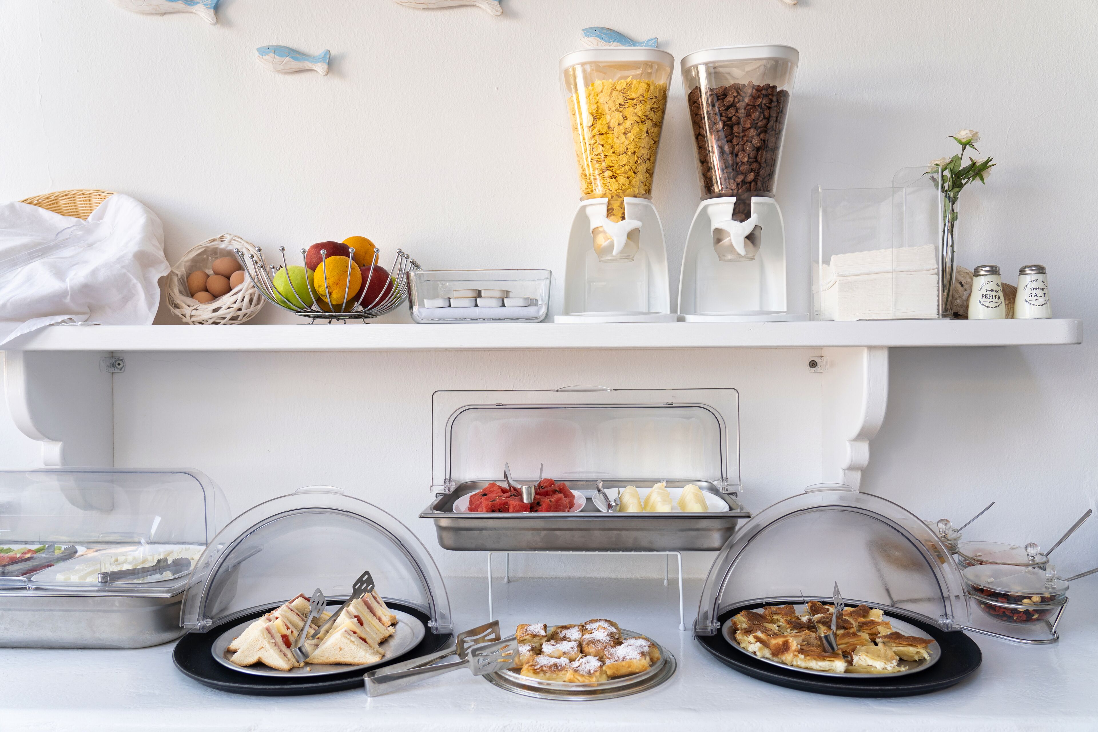 Een buffet met diverse gerechten, waaronder belegde broodjes, fruit en een koffiehoek.