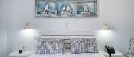A bedroom with a bed, two nightstands, a wall-mounted phone, and a decorative wall piece above the bed.