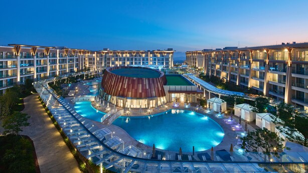 Un hotel con piscina, varios balcones y un edificio distintivo de techo curvo.