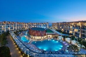 A hotel with a swimming pool, multiple balconies, and a distinctive building with a curved roof. - Marriott Jeju Shinhwa World Hotels & Resorts (Seogwipo)