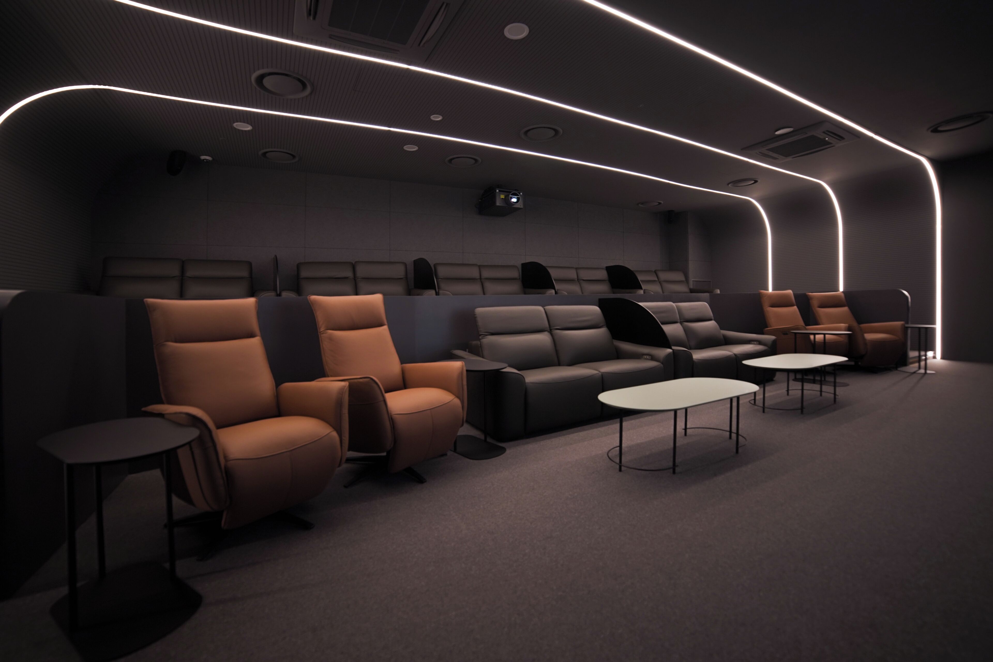 A modern cinema room with rows of seating, a projector, and ambient lighting.