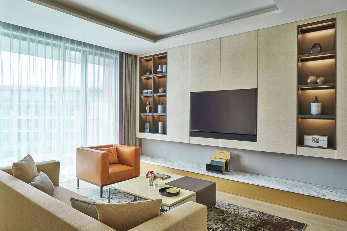 A modern living room with a sofa, coffee table, and TV mounted on the wall.