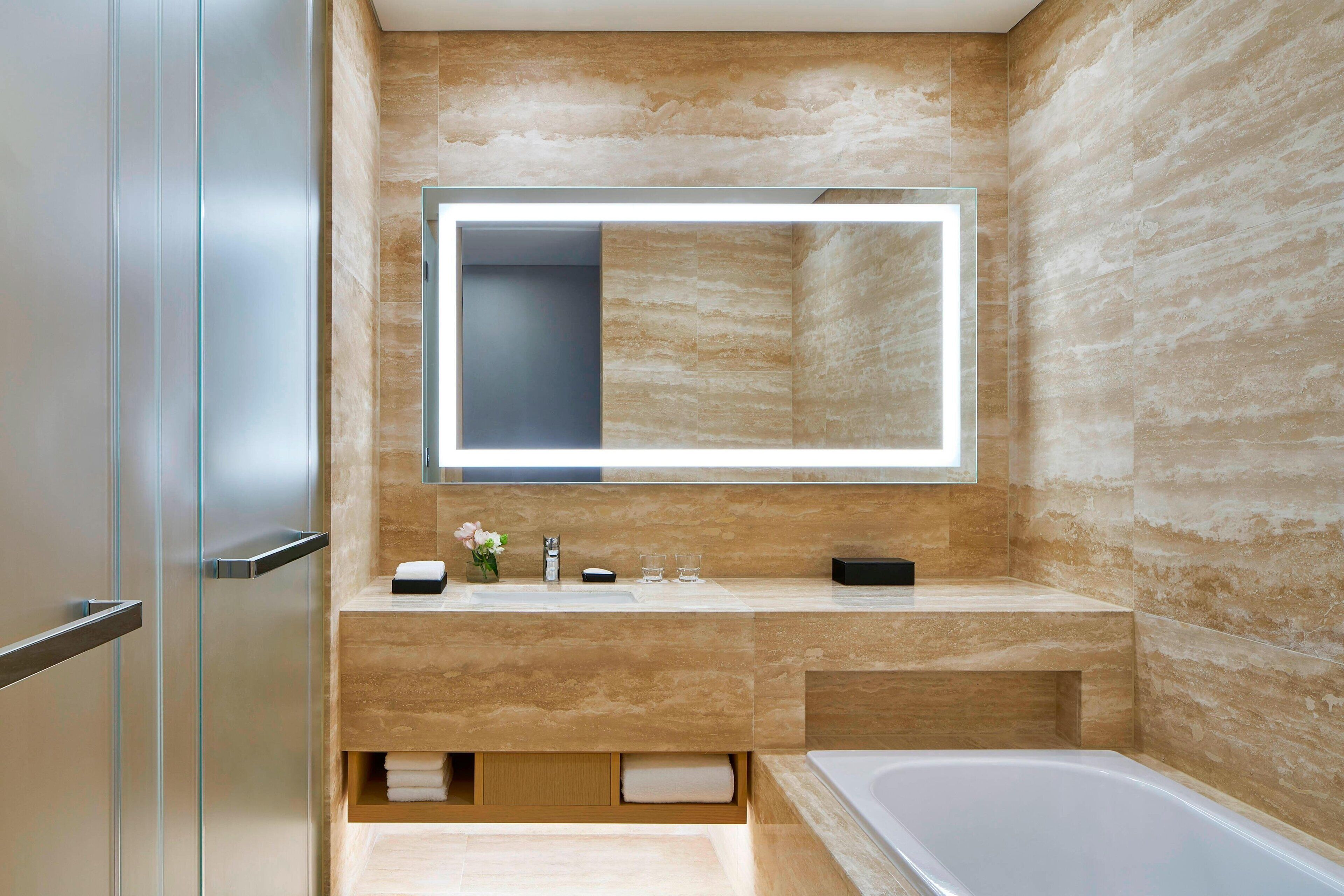 Un baño moderno con un espejo grande, una bañera y un tocador con perchero.
