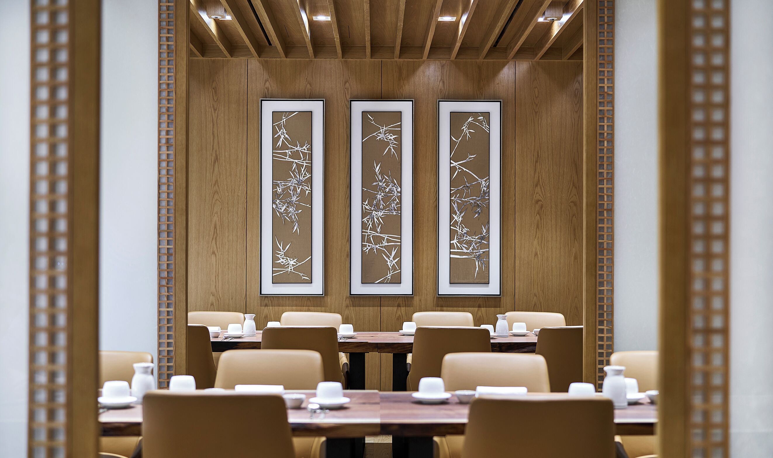 A conference room with wooden paneling, three framed wall art pieces, and a table set for a meeting.