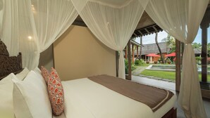 A bed with white linens and a brown bedspread, a wooden headboard, and a canopy with sheer white curtains. - Villa Mannao by Villa Finder (Kerobokan)