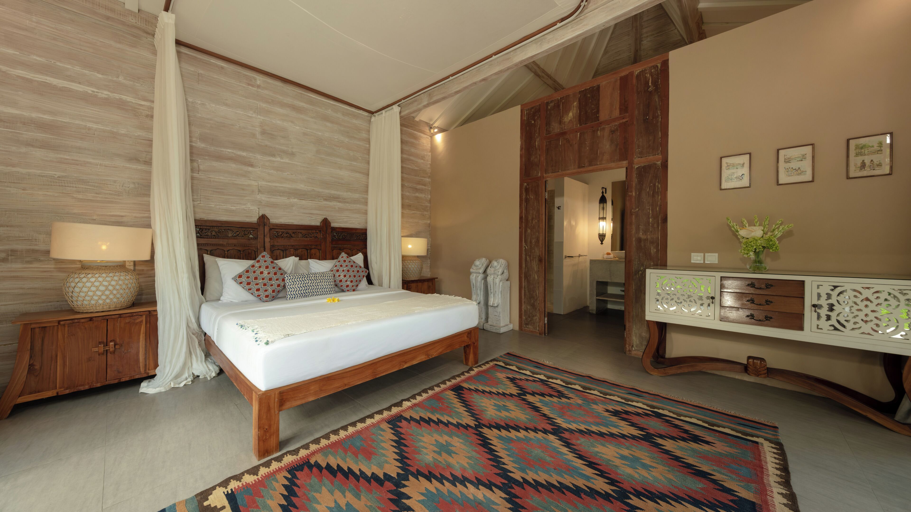 A bedroom with a bed, nightstands, a dresser, and a patterned rug.