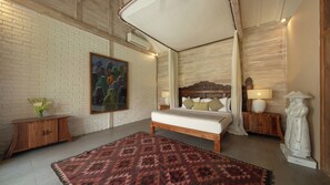 A bedroom with a bed, a nightstand, a lamp, a statue, and a painting on the wall.