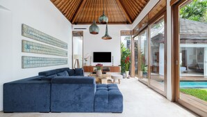 Una sala de estar moderna con un sofá modular, techo de madera y un televisor sobre un mueble de madera.