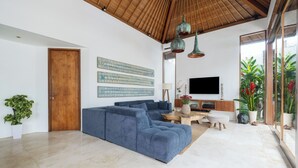 Una sala de estar moderna con un amplio sofá modular, techo de madera y un televisor de pantalla plana montado en la pared.