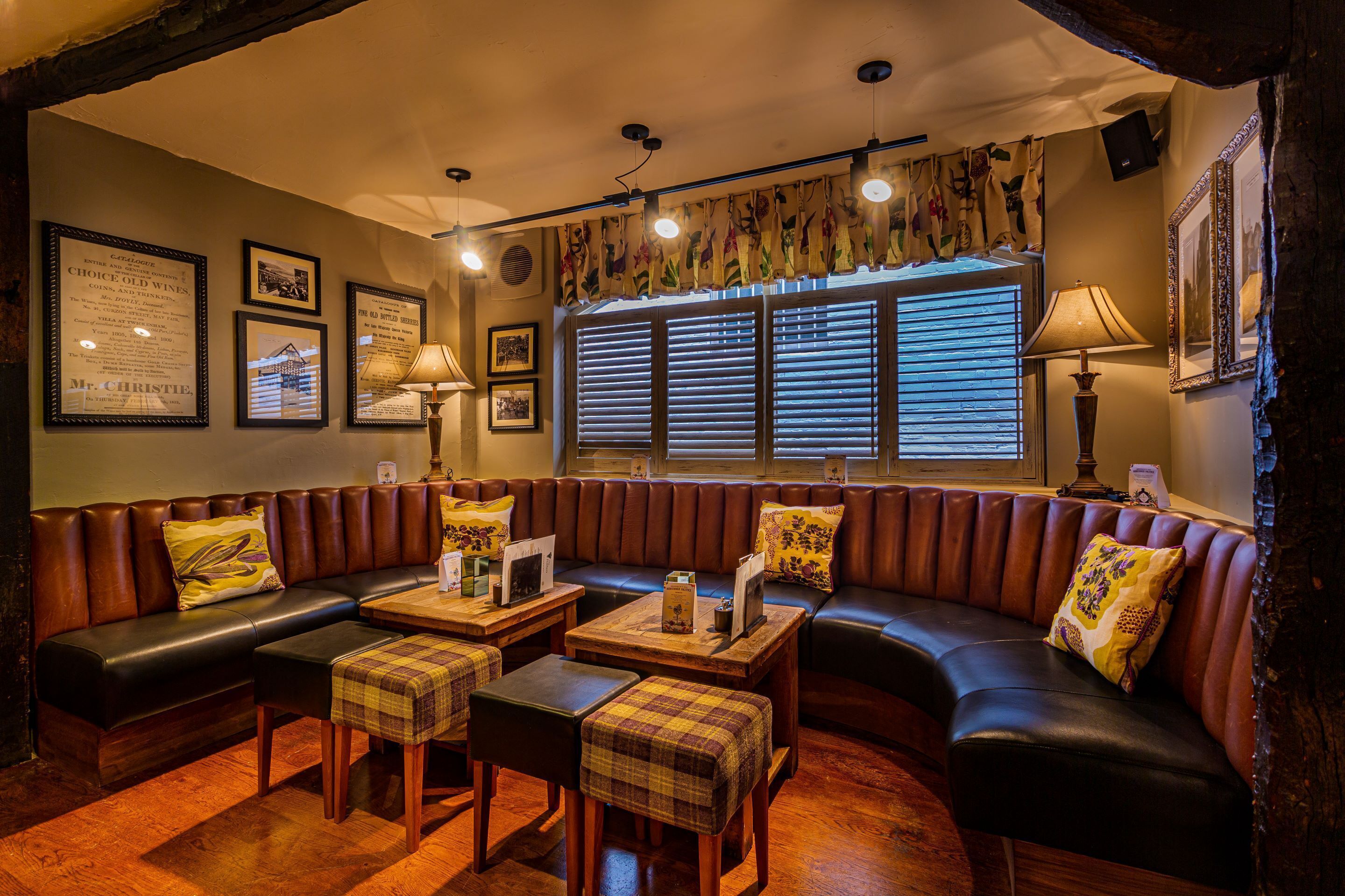 Ein gemütlicher, gut beleuchteter Lounge-Bereich mit einer Ledersofa, Karottenhocker und einem Holztisch.