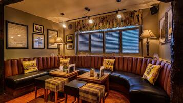 Ein gemütlicher, gut beleuchteter Lounge-Bereich mit einer Ledersofa, Karottenhocker und einem Holztisch.