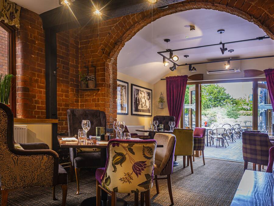 A restaurant with brick walls, wooden furniture, and a view through an archway.
