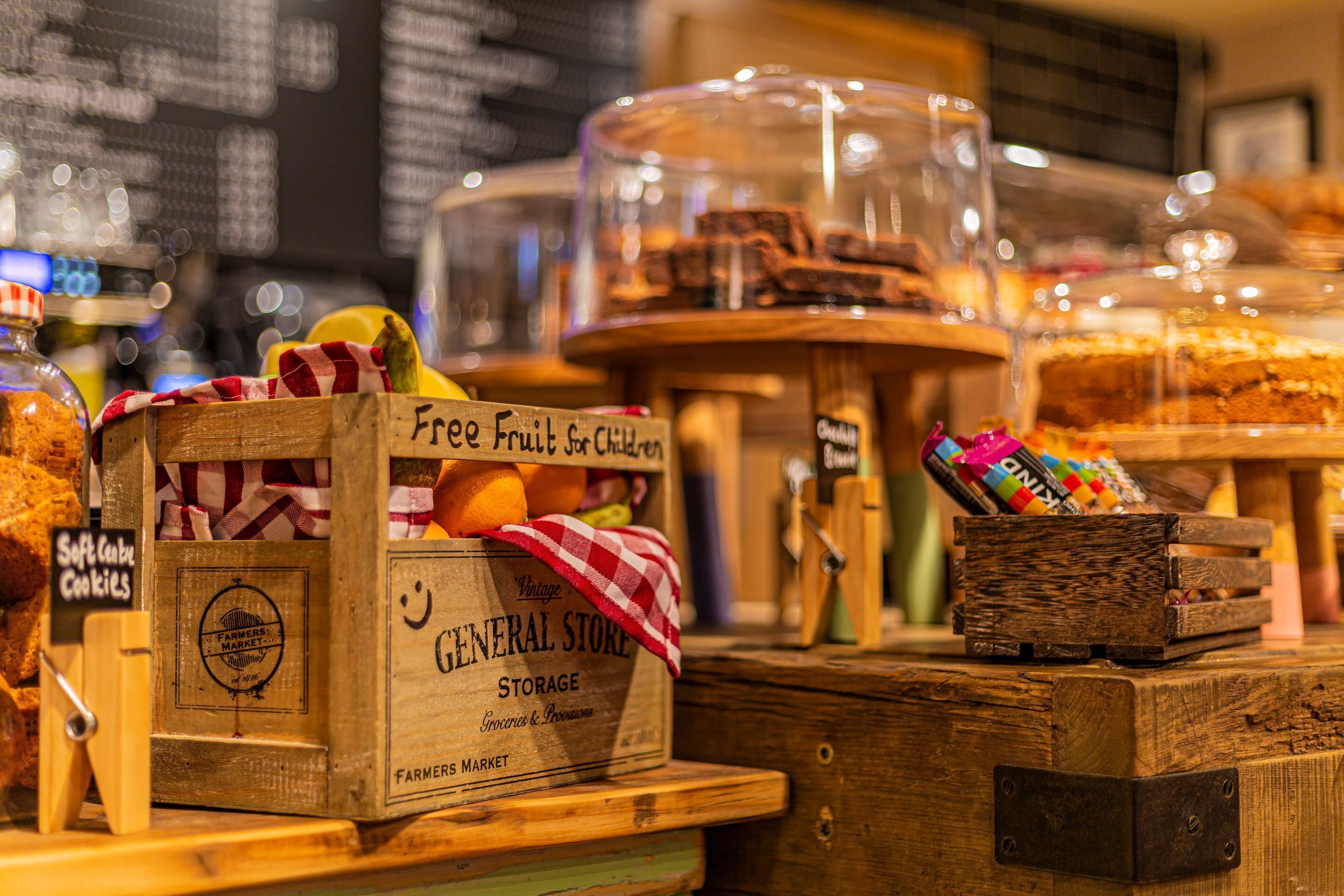 A bakery display with various baked goods and a wooden crate labeled "Free Fruit for Children".