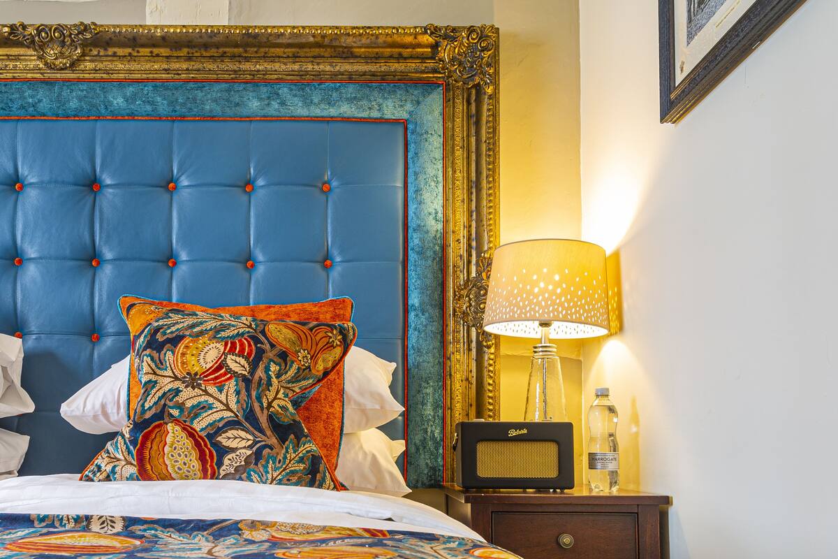 A bed with a blue headboard, a patterned bedspread, and a decorative pillow.