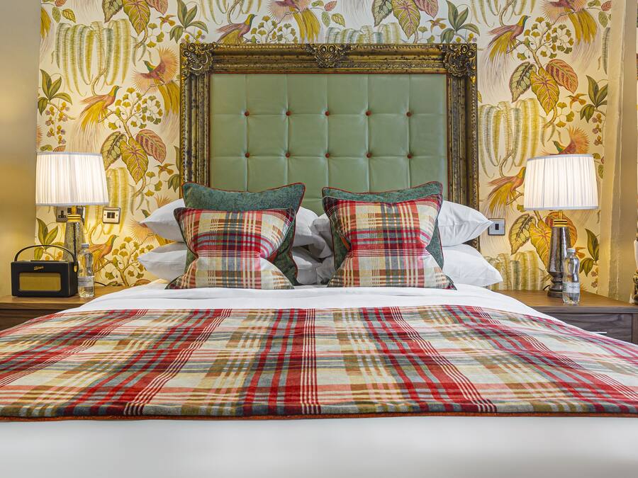 A hotel room with a large bed, two nightstands, a radio, and a wall with a floral mural.