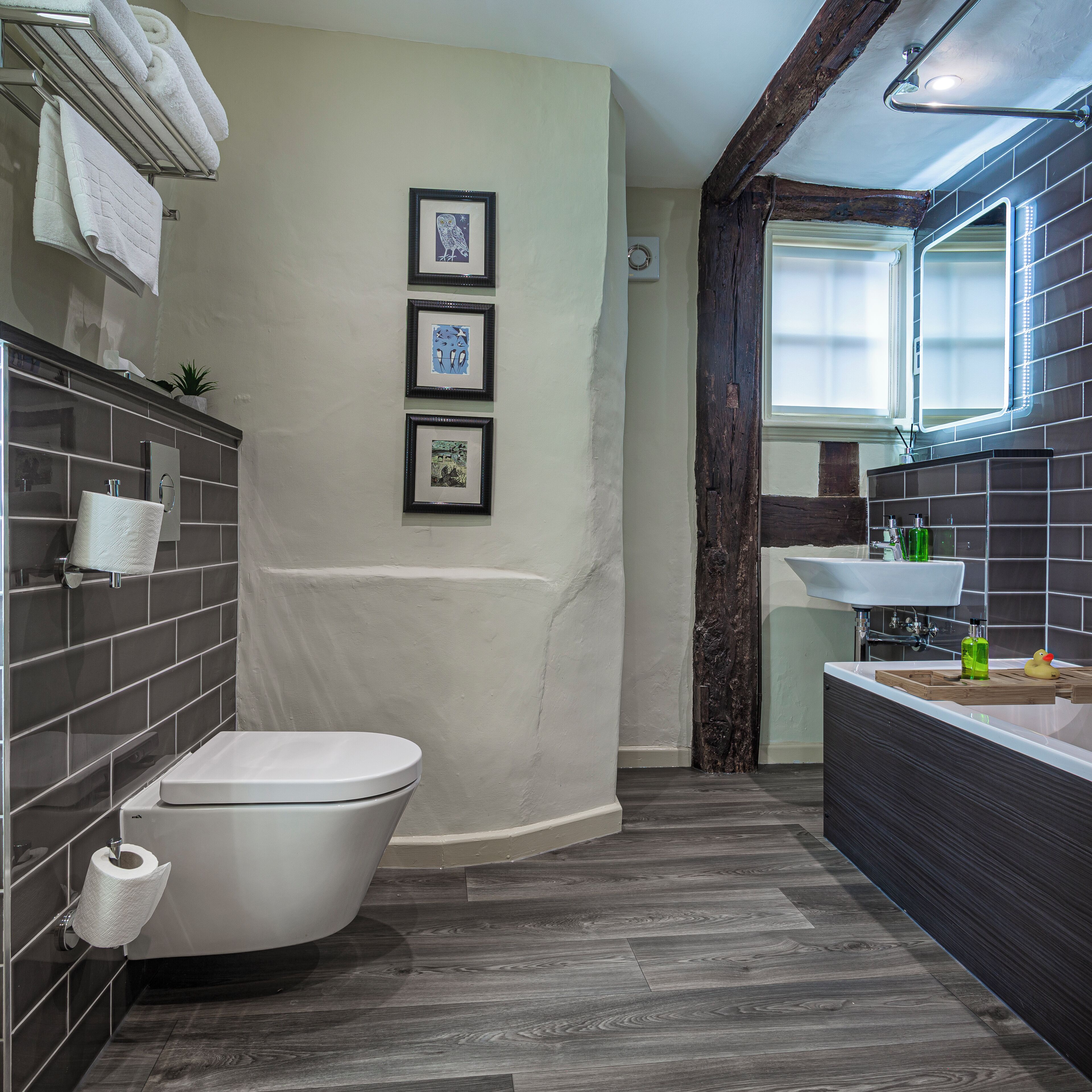 A bathroom with a toilet, sink, and framed pictures on the wall.