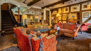 A spacious lobby with a grand staircase, comfortable seating areas, and a variety of wall-mounted lamps. - The Feathers Hotel, Ledbury, Herefordshire (Ledbury)