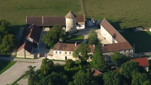 Eine Vogelperspektive eines historischen Gebäudekomplexes mit einem zentralen Turm, angrenzenden Gebäuden und umgebender Bepflanzung.