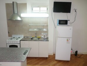 A compact kitchen with a stove, sink, and microwave. - Casas en MDQ Cordoba by EF (Mar del Plata)