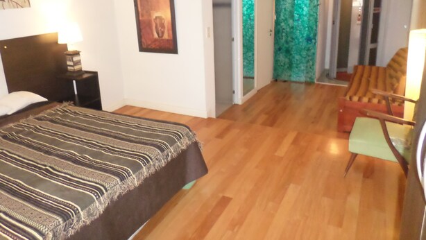 A bedroom with a bed, a nightstand, a chair, and a door leading to a bathroom. - Casas en MDQ Cordoba by EF (Mar del Plata)