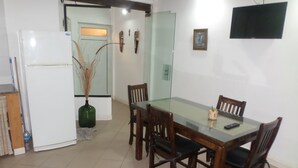 A dining area with a glass table and wooden chairs, a white refrigerator, and a green vase with dried plants. - Casas en MDQ Cordoba by EF (Mar del Plata)