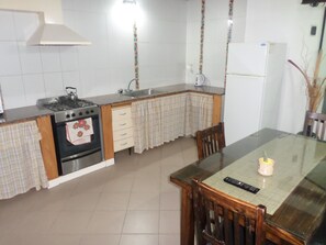 A kitchen with a stove, oven, sink, and a dining table with chairs. - Casas en MDQ Cordoba by EF (Mar del Plata)