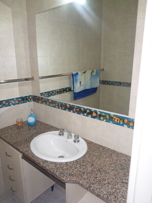 A bathroom with a granite countertop, a white sink, a mirror, and a towel rack. - Casas en MDQ Cordoba by EF (Mar del Plata)