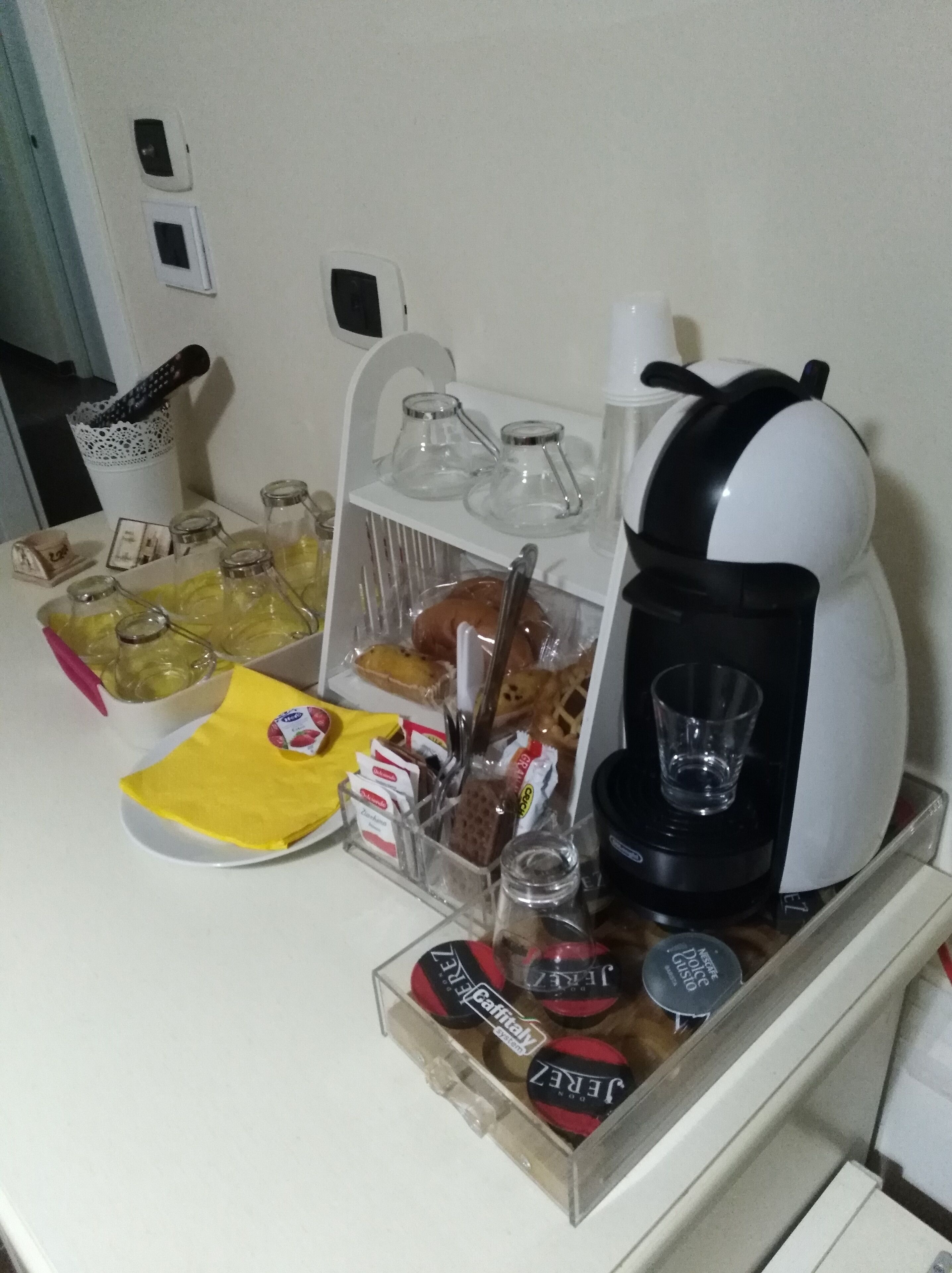 Un angolo cottura con una macchina per caffè, un barattolo di vetro e diversi alimenti.