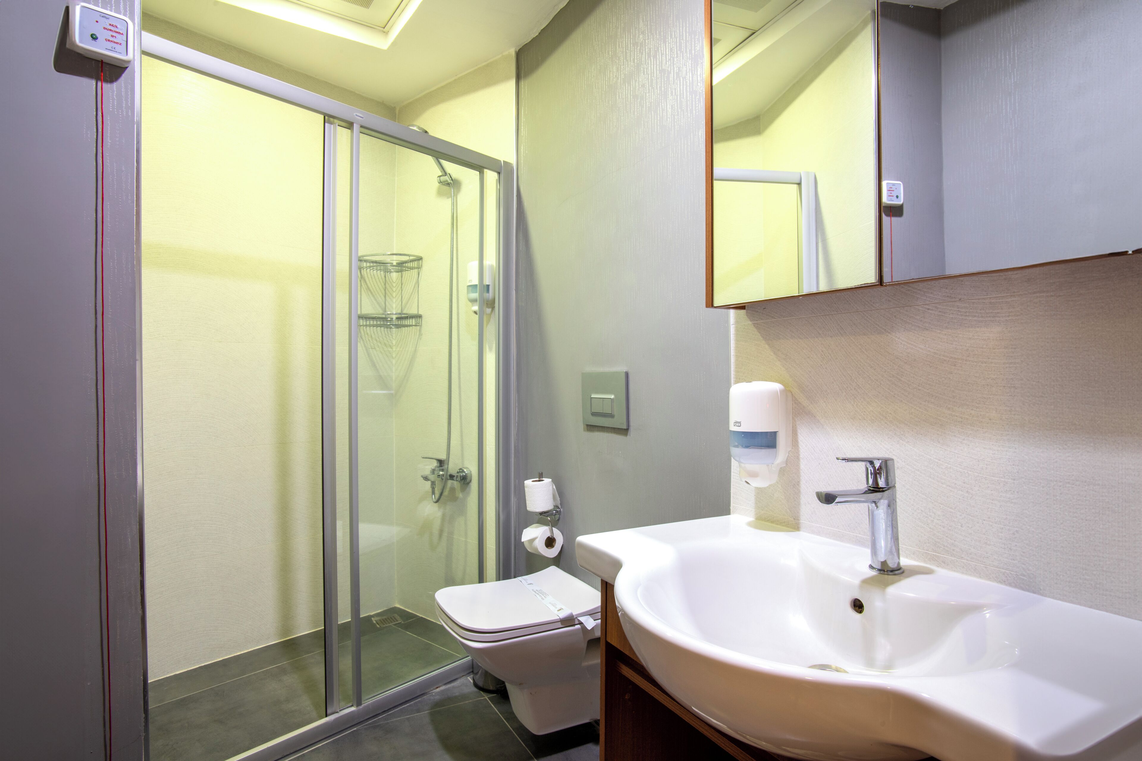 Une salle de bain avec une douche à parois de verre, des toilettes, un lavabo et un miroir.