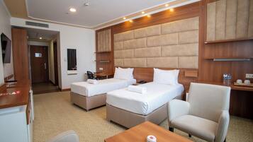 A hotel room with two beds, a desk, a chair, and a television.