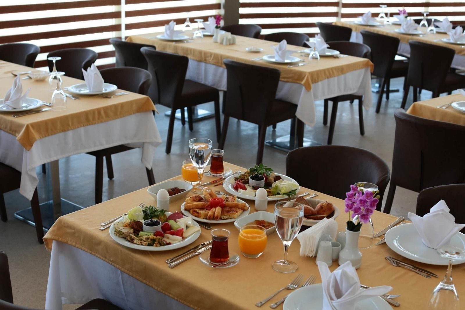 A dining area with tables set for breakfast, including plates of food, drinks, and cutlery.