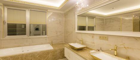 Un baño con un espejo grande, dos lavamanos y una bañera.