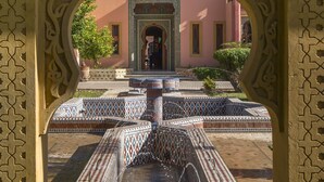 Un patio con una fuente, un arco ornamentado y un edificio al fondo.