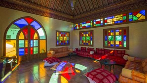Una habitación con techo abovedado, vidrieras de colores y un área de estar con sofás y una mesa de centro.