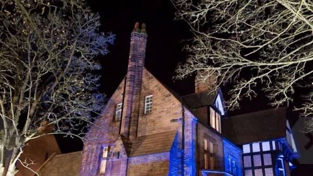 A historic building with a steeply pitched roof, multiple chimneys, and a mix of brick and timber framing.