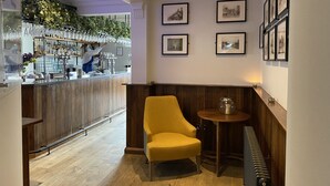 A bar area with wooden paneling, a yellow armchair, and framed pictures on the wall.