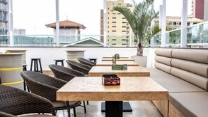 A rooftop terrace with wicker chairs, a wooden table with a smartphone, and a sofa. - Hotel Villa Smart (Fortaleza)