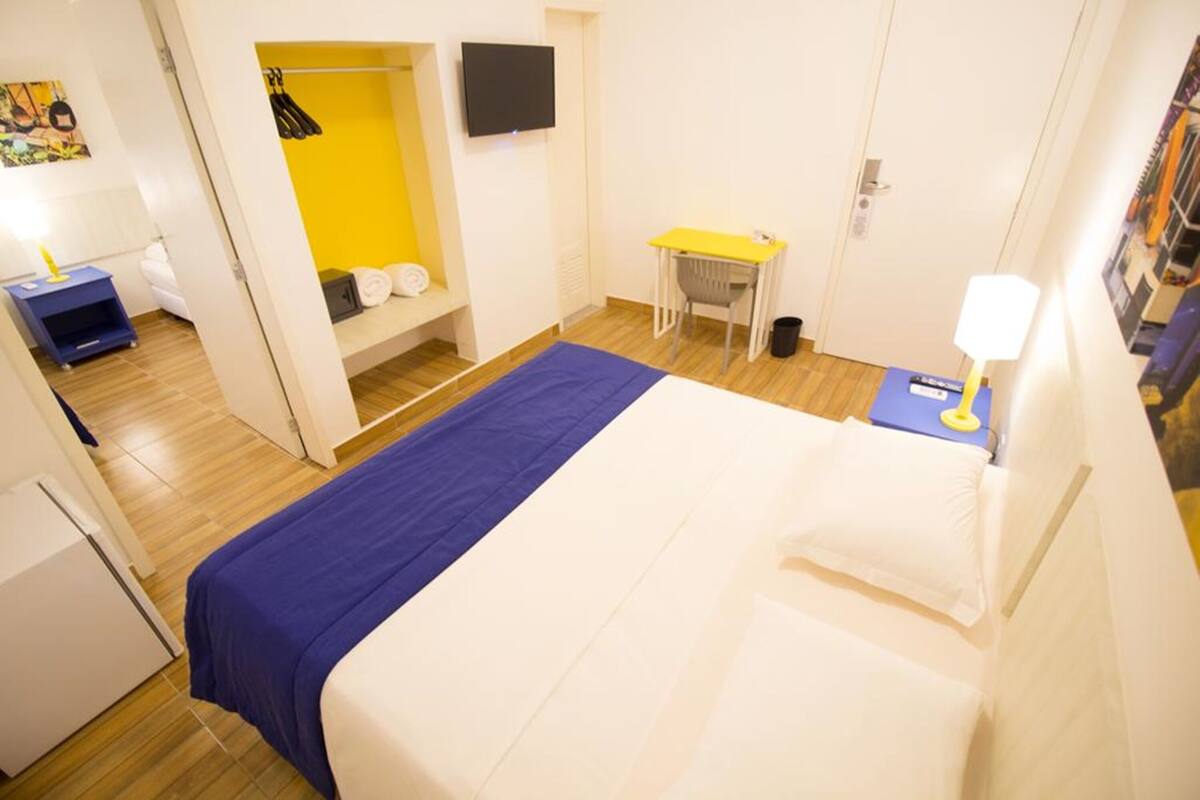 Hotellihuone, jossa on sänky, työpöytä, tuoli, televisio ja vaatekaappi.