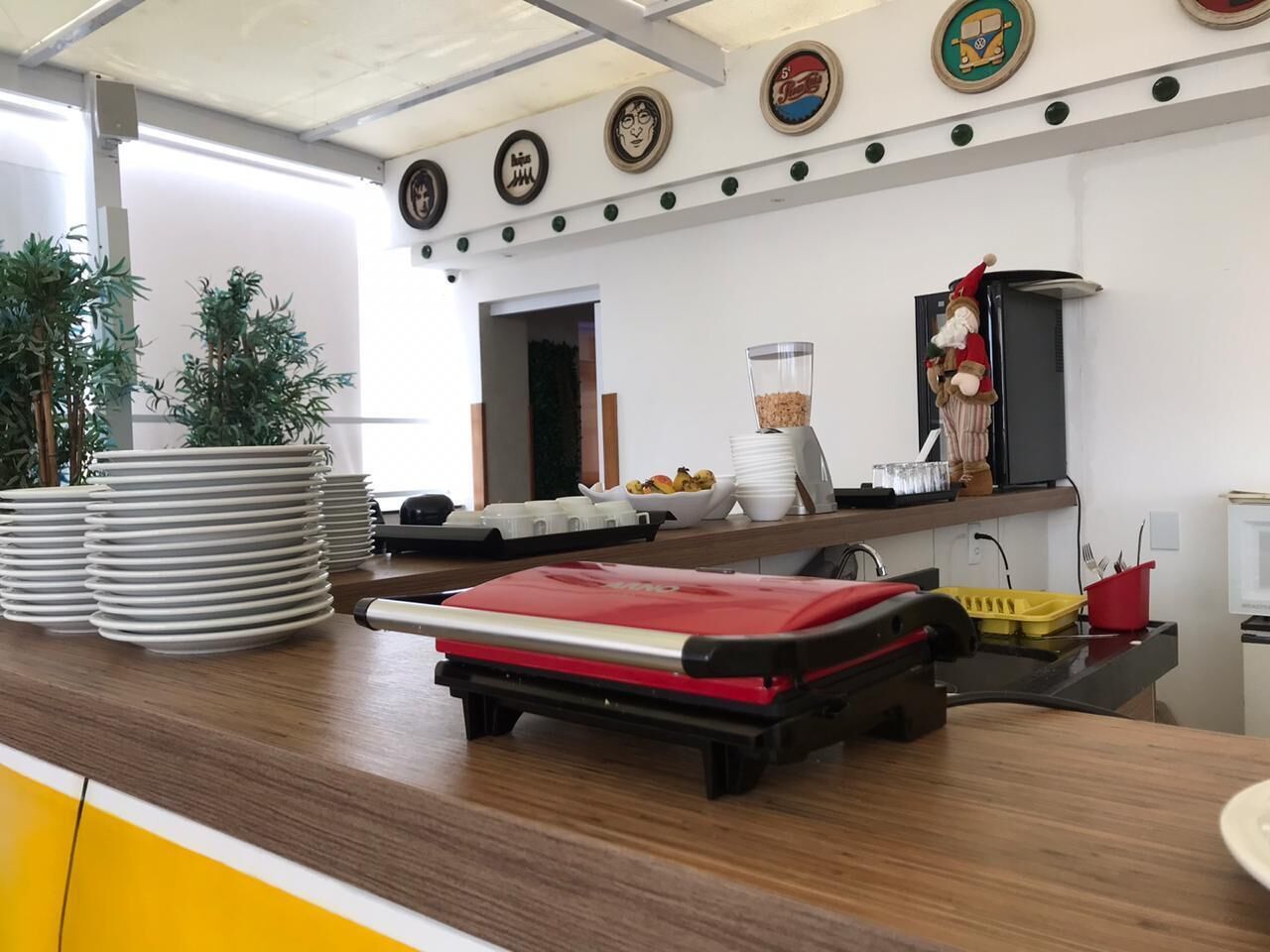 A kitchen area with a counter, stacked plates, a red appliance, and a decorative figure.