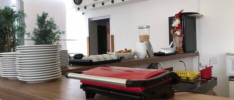 A kitchen area with a counter, stacked plates, a red appliance, and a decorative figure.
