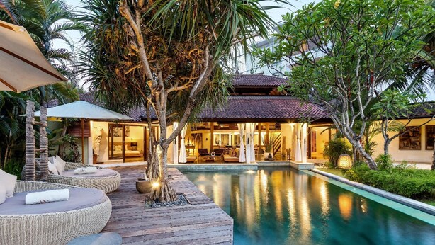 Ein Resort mit Schwimmbad, Holzterrasse und tropischer Bepflanzung.