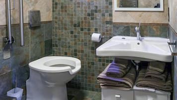 A bathroom with a toilet, sink, and tiled walls.