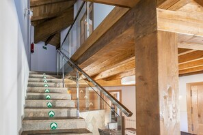 Una escalera con barandillas de cristal y vigas de madera que conduce a un piso superior.