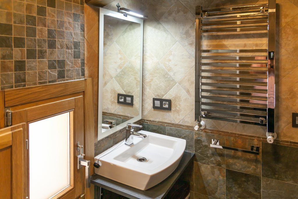 A bathroom with a white sink, a mirror, and a towel rack.